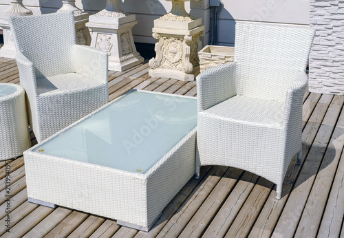 Rattan table and chaise longues near modern swimming pool, closeup photo