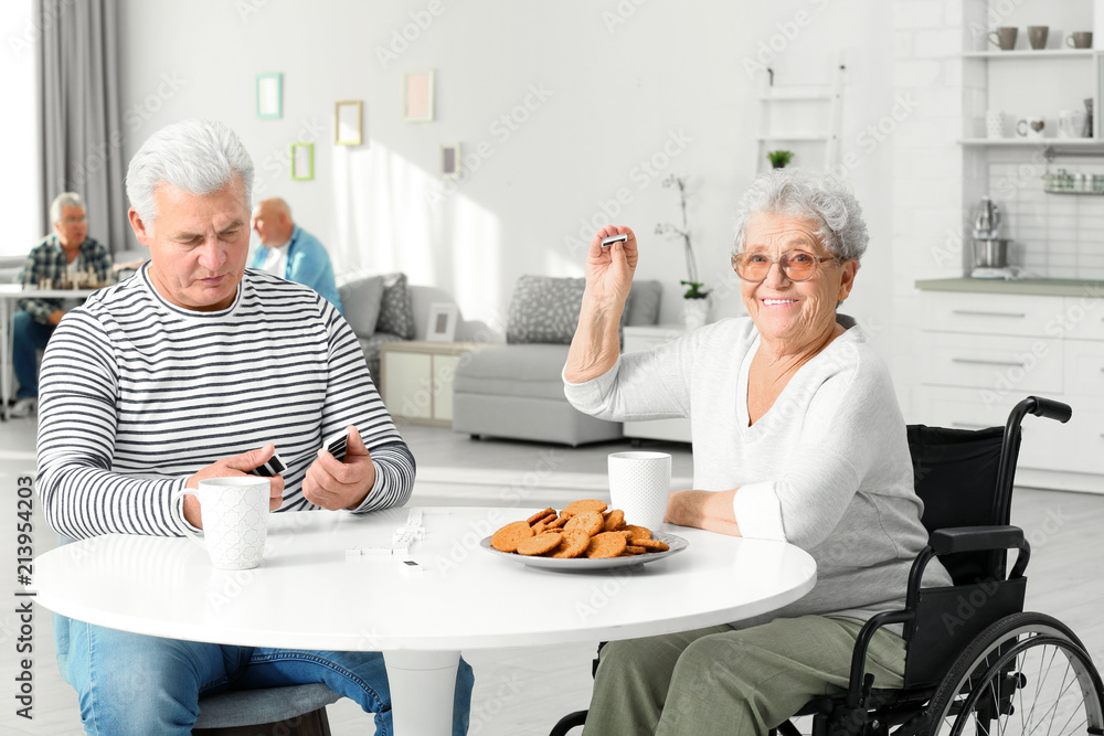 Senior woman playing dominoes with her friend while having breakfast at care home Senior woman playing dominoes with her friend while having breakfast at care home