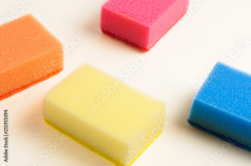 Scattered four red blue orange and yellow sponges for dishwashing on white background. Cleaning concept