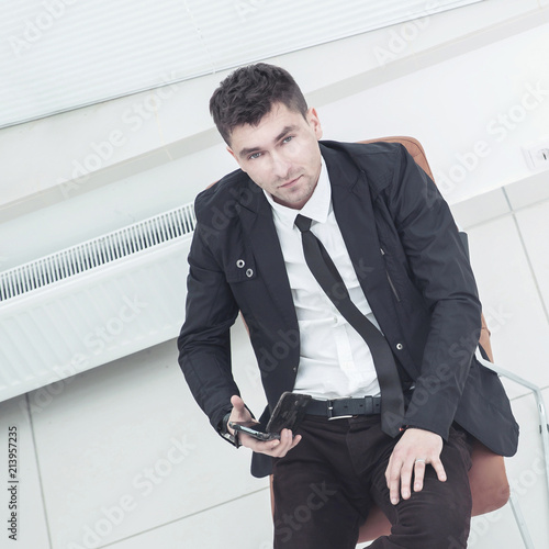 successful Manager with a smartphone sitting in an office chair in the spacious office