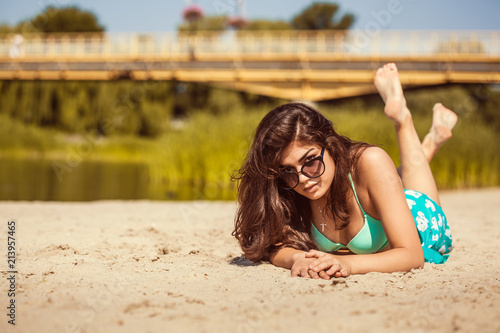 hot sexy brunette in a turquoise swimsuit on the sandy beach