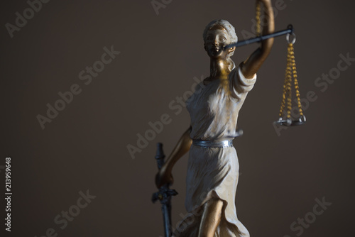 Justice Themis goddess sculpture on dark brown background.