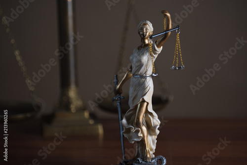 Justice Themis goddess sculpture on dark brown background.