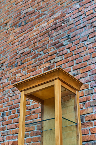 Wooden showcase with glass shelves on a brick wall background photo