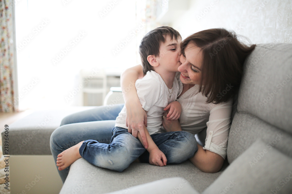 beautiful brunette mom and son hugging sofa