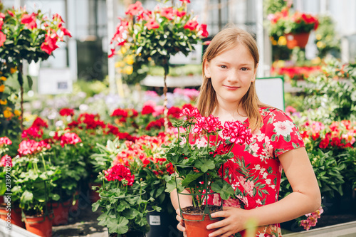 Adorable little girl choosing flowers in garden center