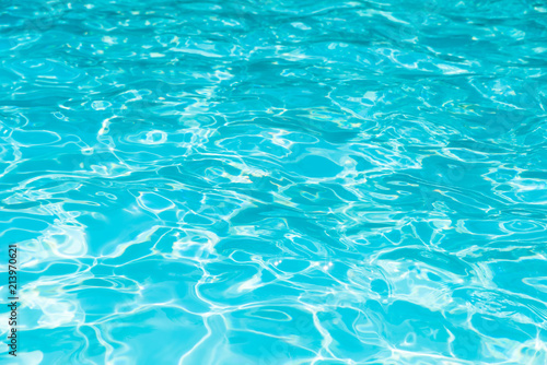 Blue and bright water surface and ripple wave with sun reflection in swimming pool