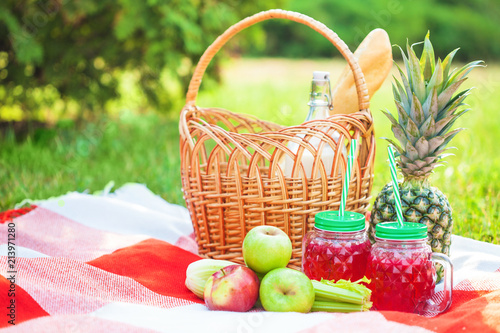 Fototapeta Naklejka Na Ścianę i Meble -  picnic basket, fruit, juice in small bottles, apples, milk, pineapple summer, rest, plaid, grass Copy space