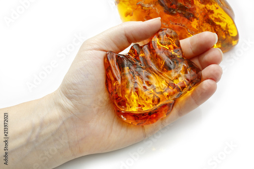 Beautiful pieces of amber one on a white background another in the hand. A luminous piece of amber in the palm of your hand. Sun stone. Petrified resin natural crystal material for jewelry. Vintage photo