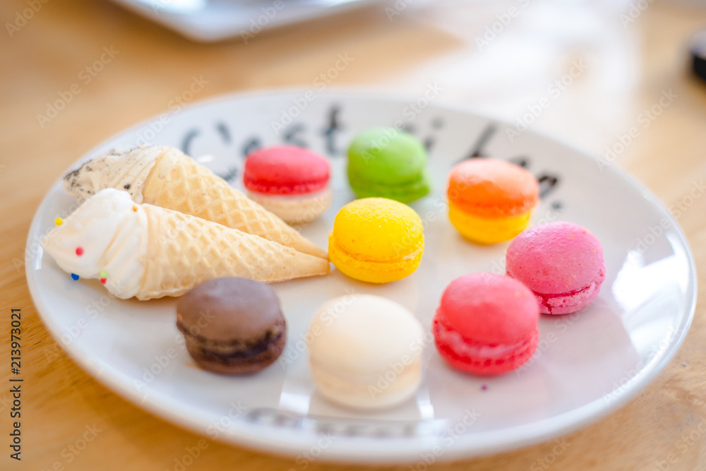 close up Mix color of macaroon on wihte plate with french language put on soft wooden table close up Mix color of macaroon on wihte plate with french language put on soft wooden table