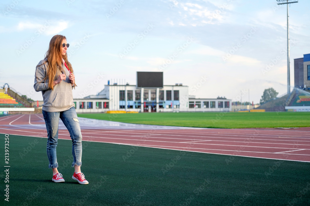 Redhead white hippie style young woman with american flag bandana, tied on neck, enjoying sunlight on athletic stadium.