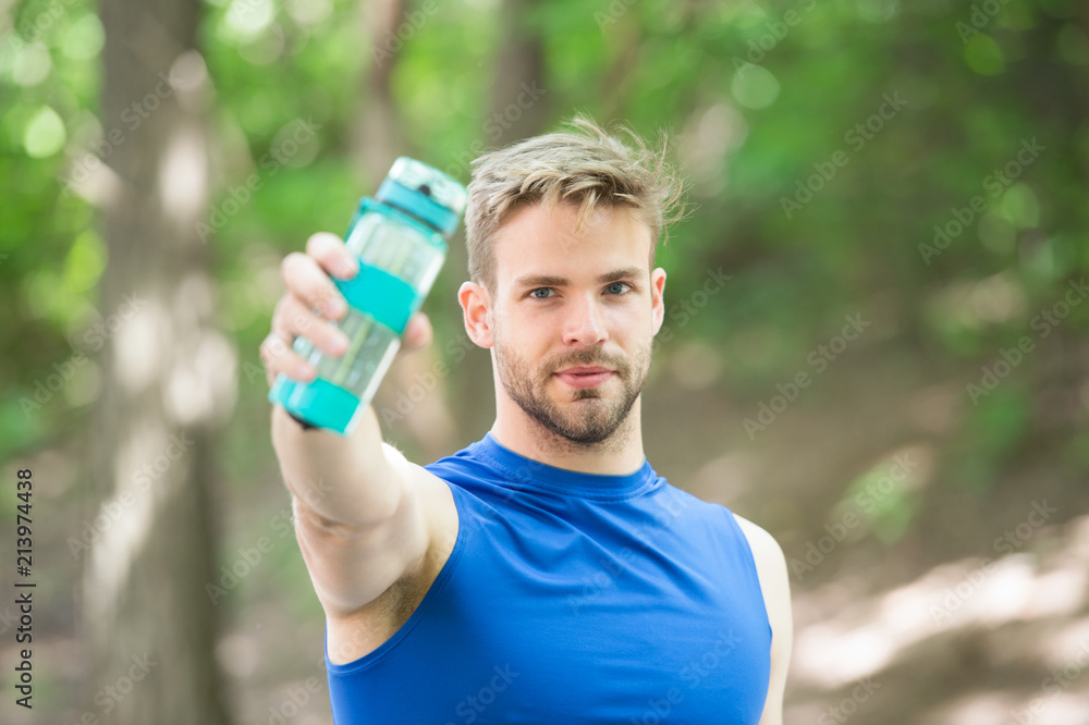 Towards a healthier lifestyle. Athlete drink water after training in park. Man athletic appearance holds bottle with water. Man athlete cares about water balance. Sport and healthy lifestyle Towards a healthier lifestyle. Athlete drink water after training in park. Man athletic appearance holds bottle with water. Man athlete cares about water balance. Sport and healthy lifestyle