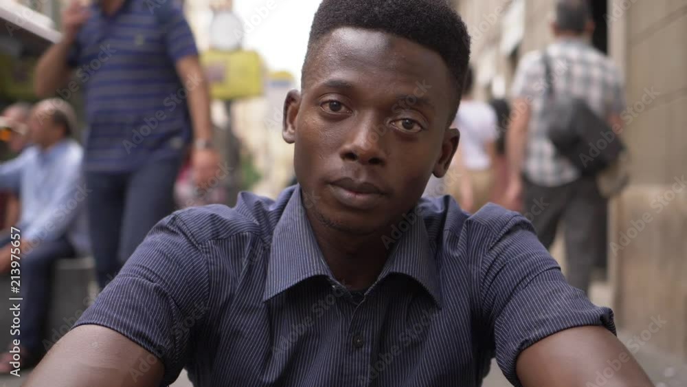 pensive sad young black american man staring at camera in a crowded street pensive sad young black american man staring at camera in a crowded street