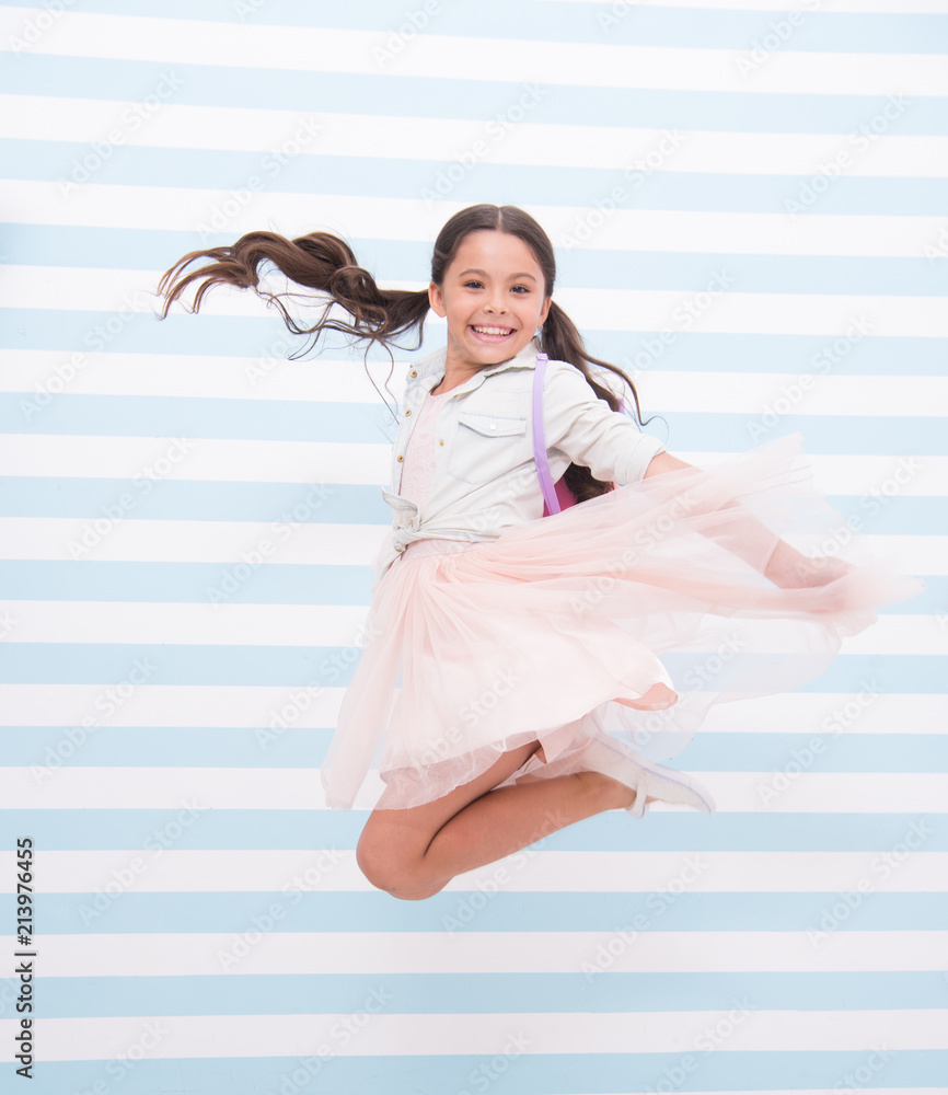 Full of energy. Girl happy face ponytail hairstyle jumps in air. Kid girl  stylish dress jumping