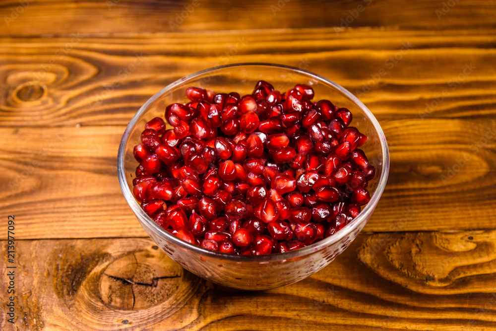 Seeds of the garnet fruit in glass bowl on wooden table Seeds of the garnet fruit in glass bowl on wooden table