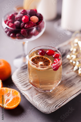 Christmas hot apple cider with cinnamon, cranberry and orange on a wooden tray