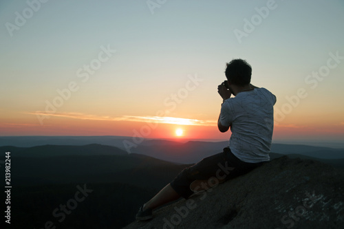 The silhouette of a man taking a photo of the sunset on your smartphone.