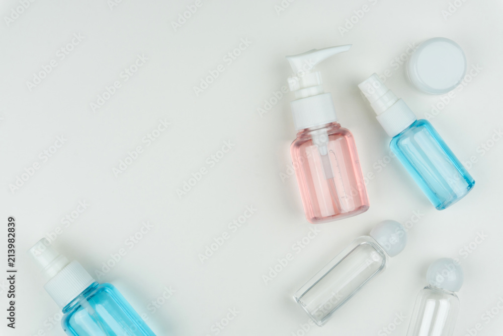 top view of the pink, blue and clear liquid containers with a white portable cream jar on white background top view of the pink, blue and clear liquid containers with a white portable cream jar on white background