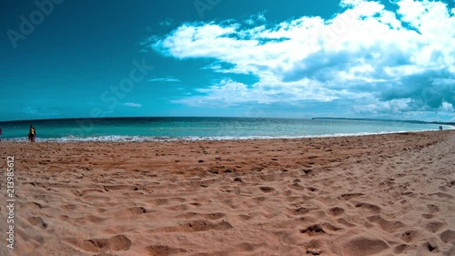 People walking by sand beach, gentle waves calm ocean, blue sky