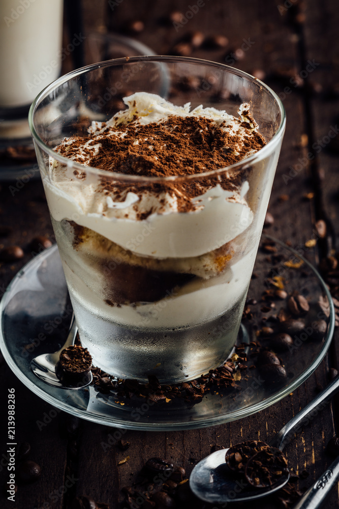 A glass of spicy latte with whipped cream and cinnamon, standing on a brown board. Coffee beans. Dark background A glass of spicy latte with whipped cream and cinnamon, standing on a brown board. Coffee beans. Dark background