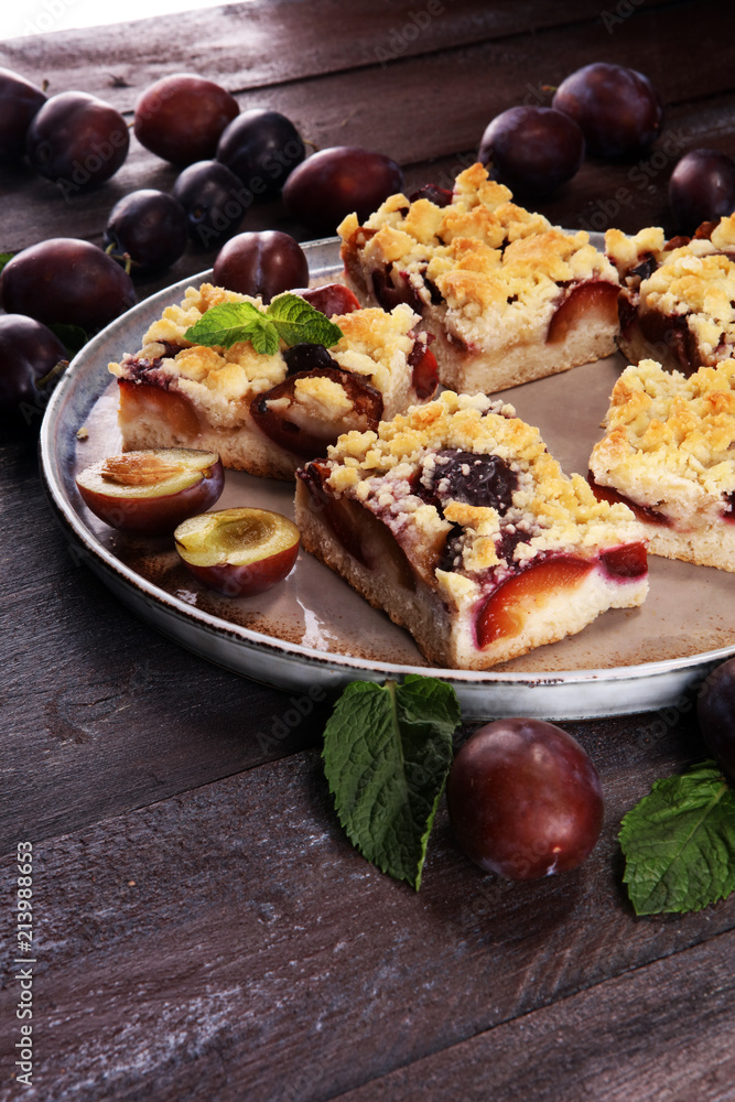 Rustic plum cake on wooden background with plums around. Rustic plum cake on wooden background with plums around.