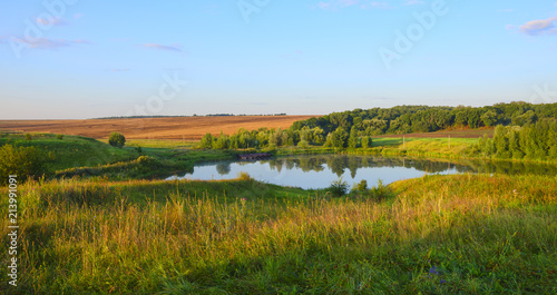 Tranquil summer landscape with beautiful river woods fields and green hills.Sunny windless morning.