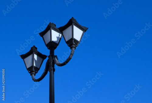 Photo of an old street lamp on a background of clear sky