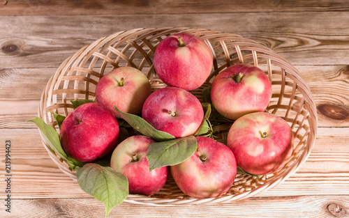 Ripe red apples with leaves in a basket. Autumn harvest. Close-up
