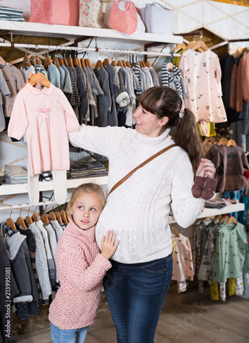 Mother and small daughter choosing clothes for baby © JackF