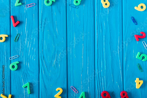 top view of colorful various numbers and paper clips on blue wooden background