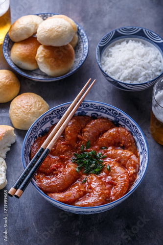 Close view of tiger prawn in chili sauce on dark background