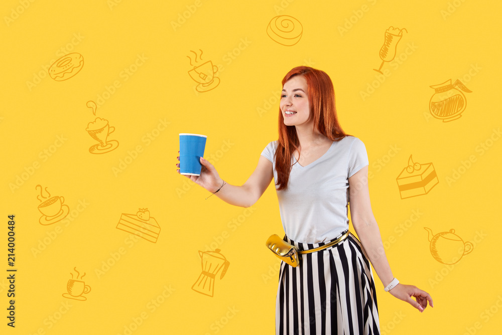 Hot tea. Positive experienced waitress smiling and looking cheerful while being at work and holding a cup of tea Hot tea. Positive experienced waitress smiling and looking cheerful while being at work and holding a cup of tea