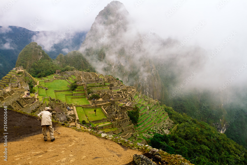 Fototapeta premium Worker spreads dirt on a terrace of Machu Picchu