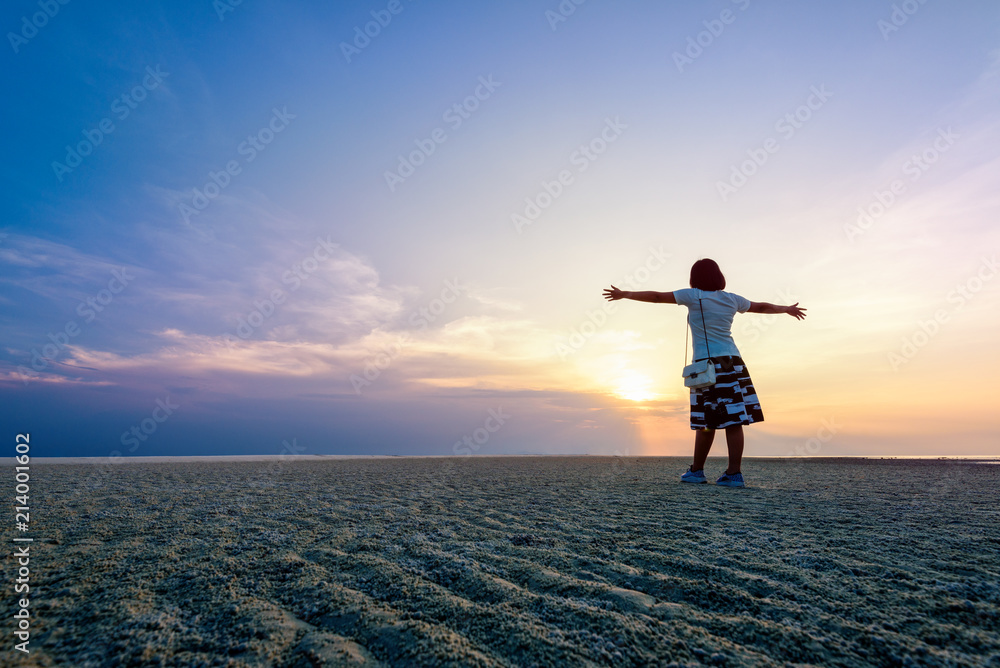 Plakat Happy woman tourist arms outstretched on the beach watching the beautiful natural landscape of colorful sky and sea during sunset at Nathon Sunset Viewpoint in Samui island, Surat Thani, Thailand