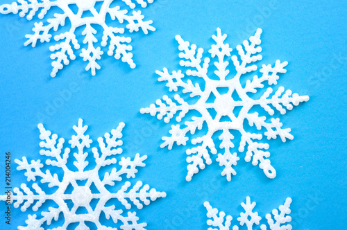 Merry christmas and happy holidays concept with close up on a bunch of white snowflakes isolated on minimalist blue background