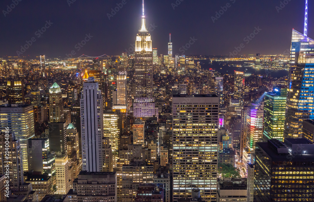 View of Manhattan skyline at night. The entire city is awash in light with the Empire State Building in center of frame.