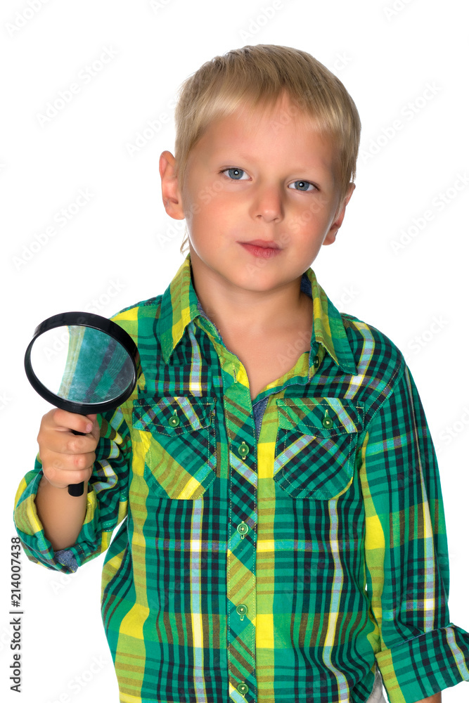 A small boy looks through a magnifying glass. A small boy looks through a magnifying glass.