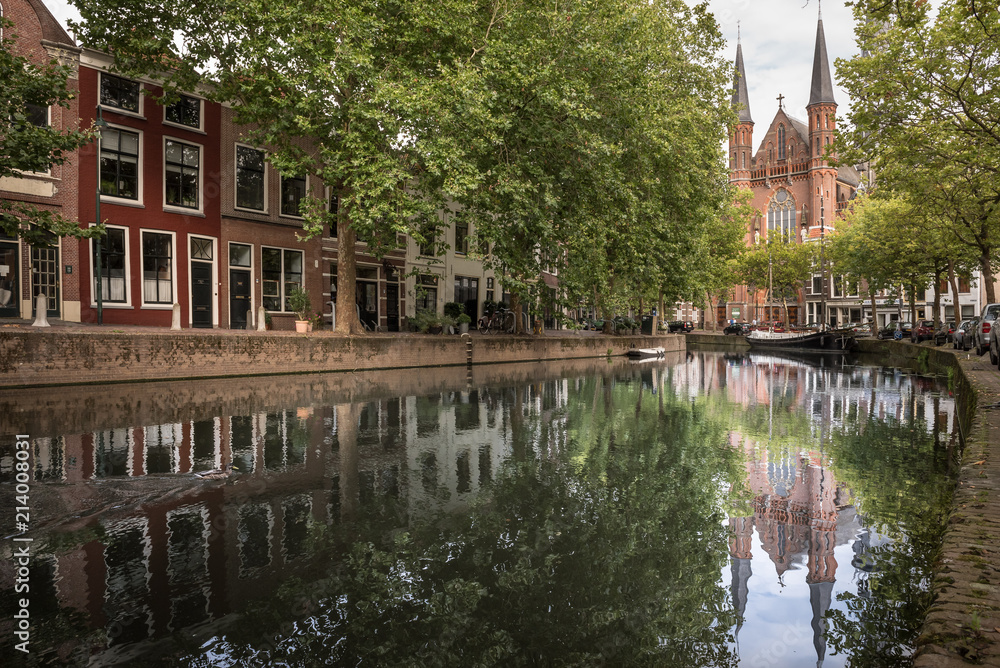 Gouwekerk church and its reflection in a water canal during a cloudy day in Gouda, Netherlands