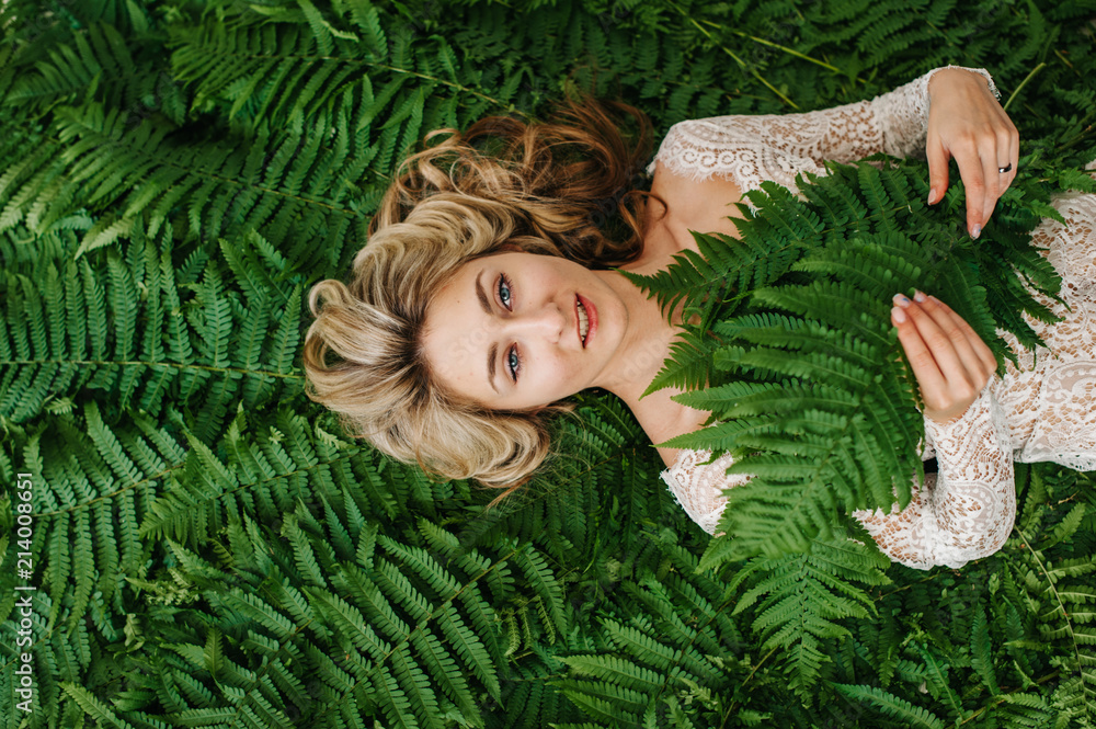 A beautiful girl lies in a fern.
