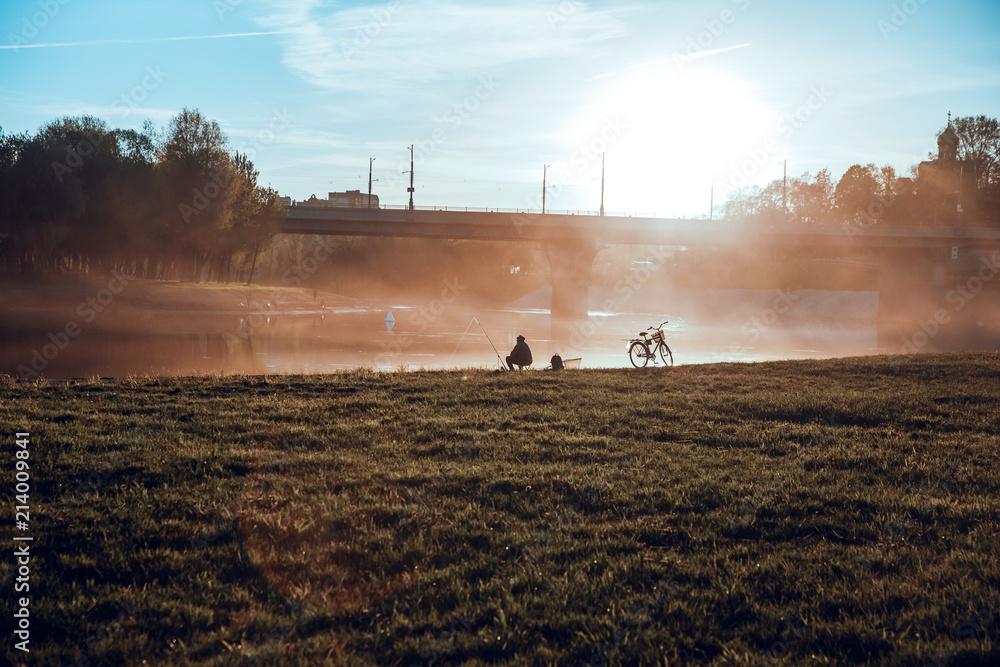 Fototapeta premium Morning.Fishing.Fisherman and fishing Rod.Bike.Embankment.City.Sky.Dawn