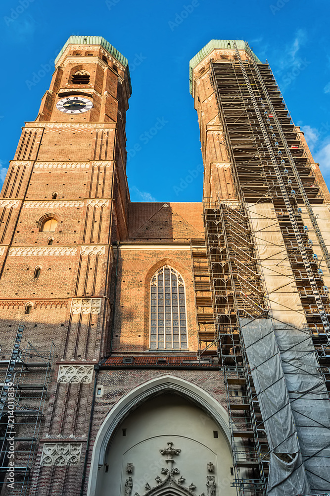 Fototapeta premium Munich, Germany June 09, 2018: The Frauenkirche (also known as: Dom zu Unserer Lieben Frau, Cathedral of Our Dear Lady, Münchner Dom, Munich Cathedral) towers over a downtown street.