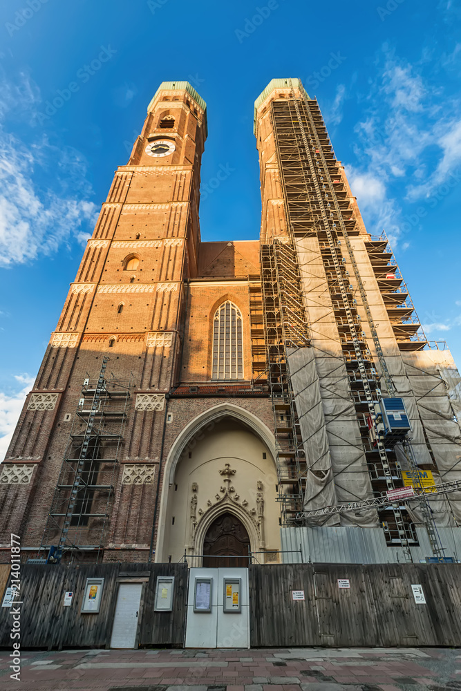 Fototapeta premium Munich, Germany June 09, 2018: The Frauenkirche (also known as: Dom zu Unserer Lieben Frau, Cathedral of Our Dear Lady, Münchner Dom, Munich Cathedral) towers over a downtown street.