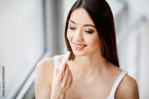 Make up. Beautiful Young woman applying lipstick