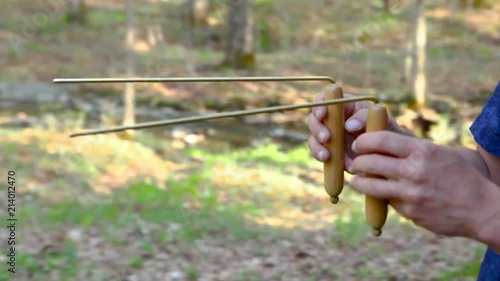 Man using dowsing rods to locate underground water or burried stones