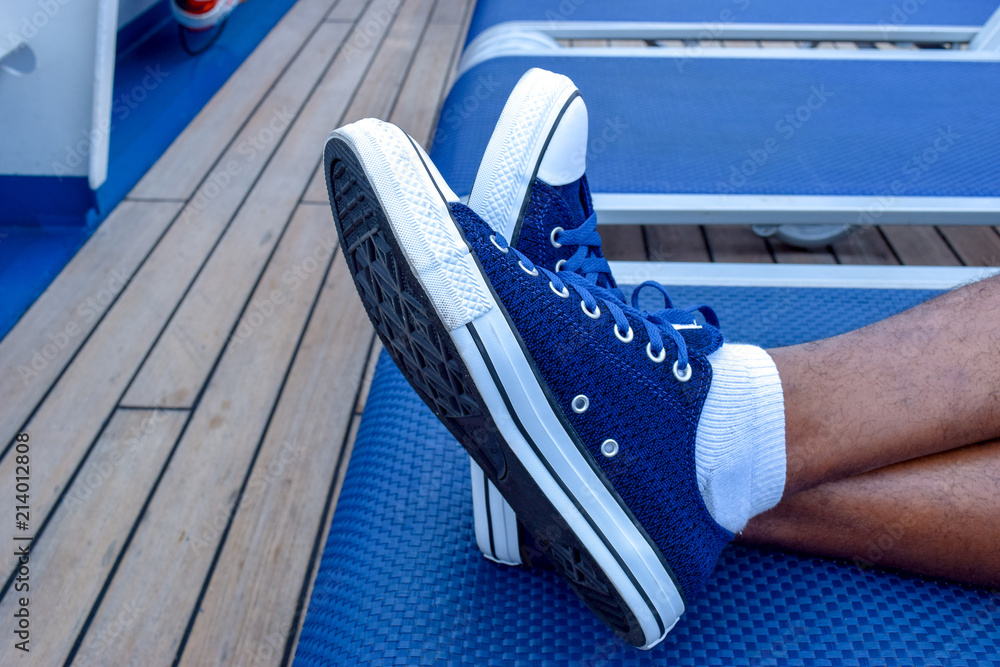 Feet crossed. Blue sneakers laced up. White socks. Lounge chair. Resting.  Relaxing. Vacation. Man. Male. Hairy legs. Concept. Casual. Content. Stock  Photo | Adobe Stock