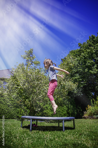 Cute little child girl jumping on a trampoline.