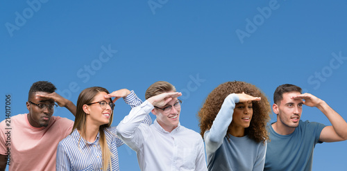 Composition of group of friends over blue blackground very happy and smiling looking far away with hand over head. Searching concept.