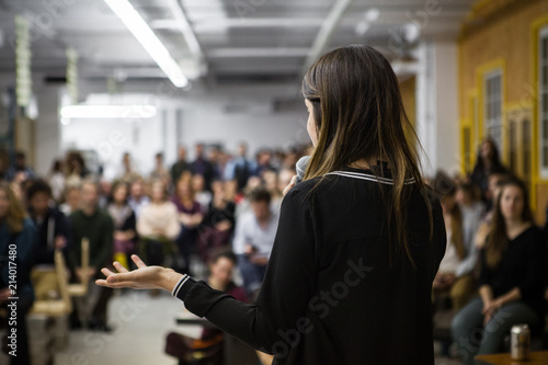 Woman gives a public speech in front of 200 people, in an industrial environment photo