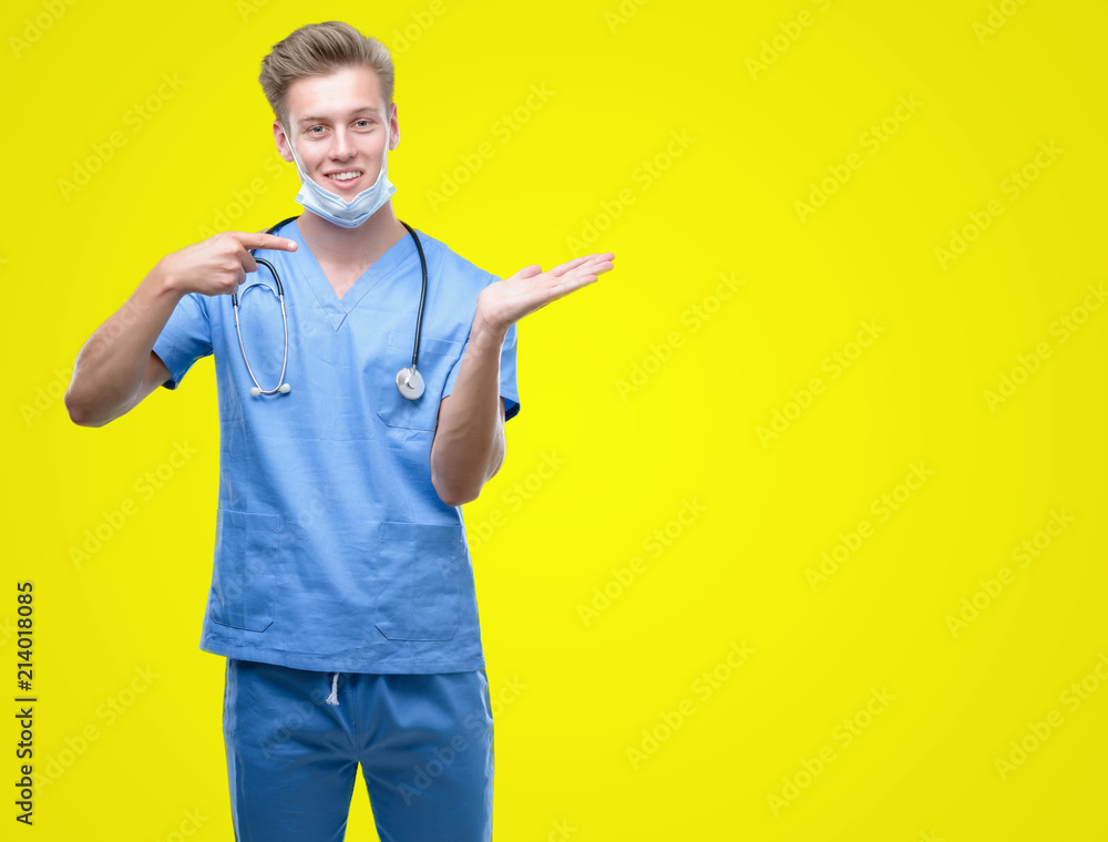 Young handsome blond doctor very happy pointing with hand and finger Young handsome blond doctor very happy pointing with hand and finger