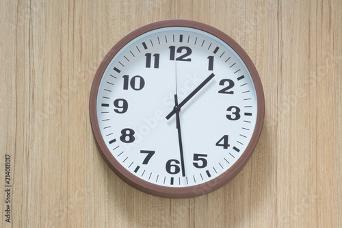 brown and white plastic clock hangs on wooden wall